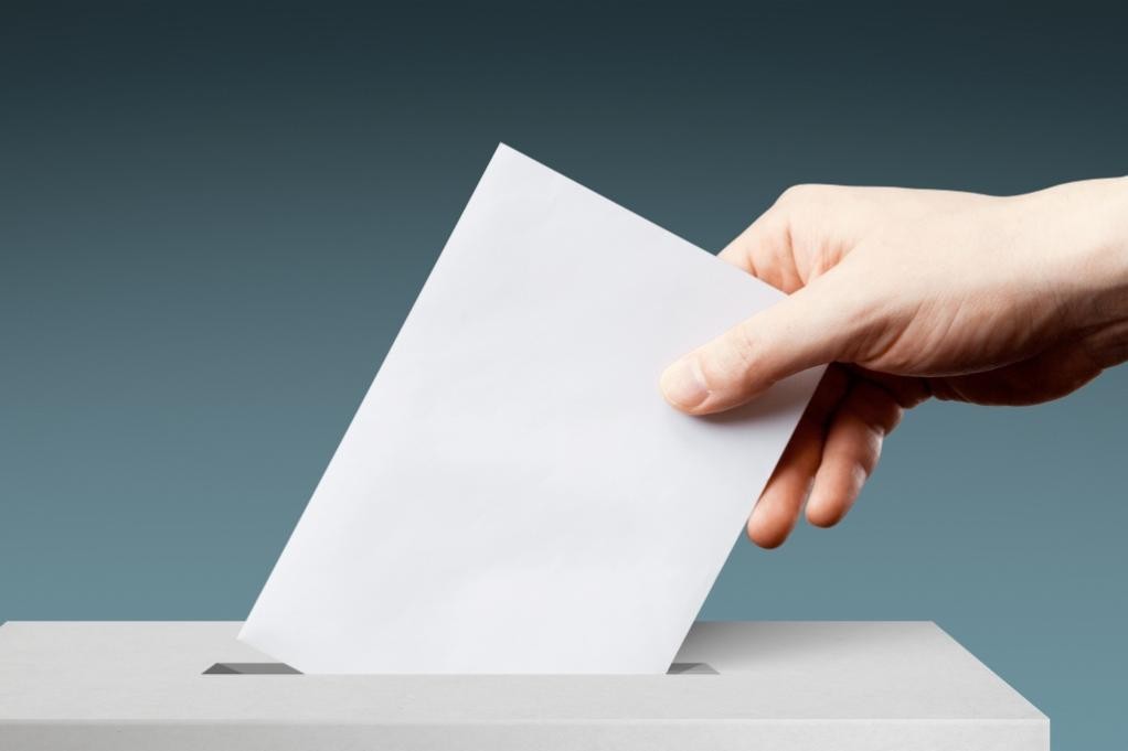 Ein Briefumschlag wird in die Wahlurne eingeworfen (Foto: iStock.com/Panorama Images)